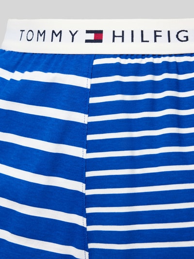 Frauenmodel trägt Regular Fit Pyjama aus reiner Baumwolle von TOMMY HILFIGER, Streifen-Optik, Logo-Applikation, Nahaufnahme Unterteil.