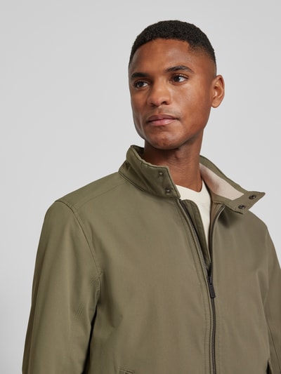 Männermodel trägt Regular Fit Blouson mit Stehkragen von Tom Tailor, olivgrün, glatte Twill-Struktur, Label Patch, Nahaufnahme Oberkörper.