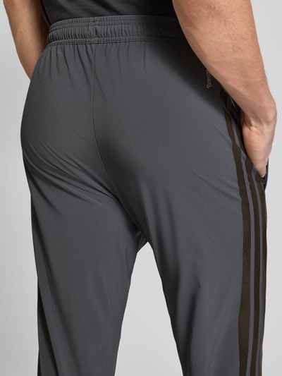 Männermodel trägt Regular Fit Jogpants mit elastischem Bund Modell 'TIRO' von adidas Sportswear in Grau, Detailaufnahme Rückansicht.