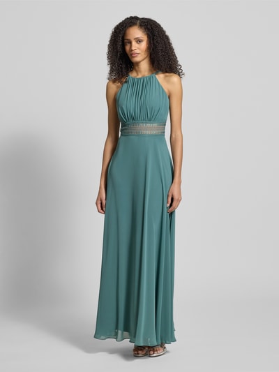 Frauenmodel trägt Abendkleid mit Raffungen von Jake*s Cocktail in Grün, taillierter Schnitt, blickdichtes Unterkleid, Ganzkörperansicht von vorne.