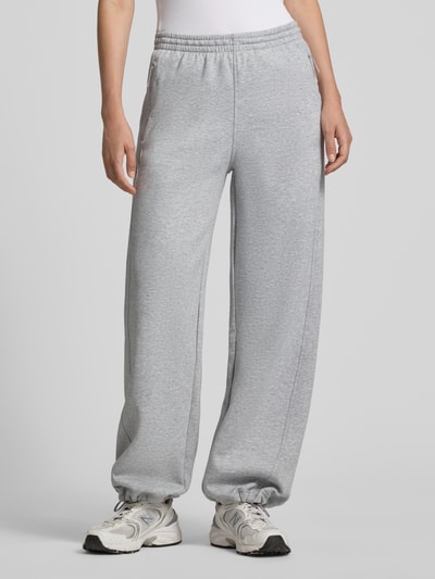 Frauenmodel trägt Regular Fit Sweathose mit Baumwoll-Anteil von Under Armour, hellgrau, lockerer Schnitt, glatte Struktur, Ganzkörperansicht von vorne. Damen Sweathose von Under Armour.
