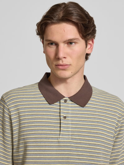 Männermodel trägt Regular Fit Poloshirt mit Label-Detail Modell 'Dion' von Carhartt Work In Progress, Reine Baumwolle, Allover-Look, Knopfleiste, Nahaufnahme Oberkörper.