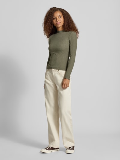 Modelka prezentuje oliwkową bluzkę z długim rękawem z dodatkiem wiskozy Slim Fit Langarmshirt mit Viskose-Anteil Modell 'EMMA' von ONLY, damska bluzka z długim rękawem, Ganzkörperansicht von vorne.