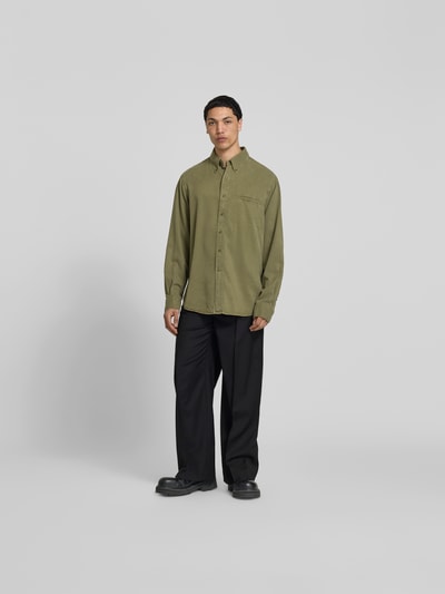 Männermodel trägt Wide Fit Stoffhose aus Woll-Mix von Filippa K, Schwarz, elastischer Woll-Mix, Bügelfalten, Gesäßtaschen, Ganzkörperansicht von vorne.