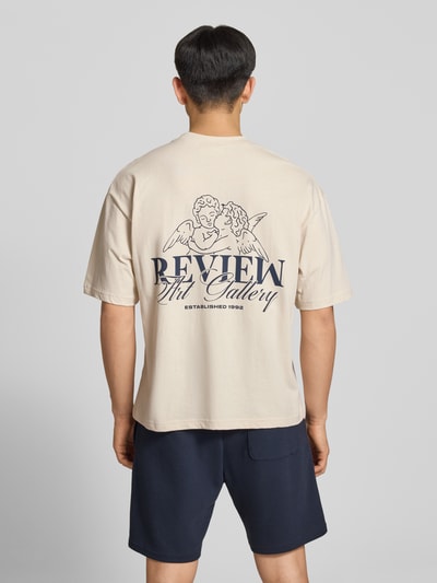 Männermodel trägt T-Shirt mit Logo-Print und Rundhalsausschnitt von REVIEW, Reine Baumwolle, Loose-Fit, Rückenlänge 69 cm, Ganzkörperansicht Rückansicht.