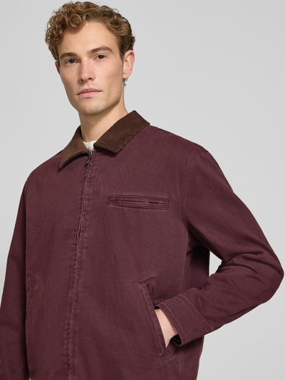 Männermodel trägt Regular Fit Jacke aus reiner Baumwolle von MCNEAL in Dunkelrot mit Cord-Umlegekragen und Reißverschluss, Nahaufnahme Oberkörper.