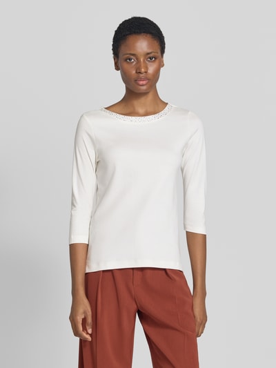 Frauenmodel trägt Regular Fit Shirt aus reiner Baumwolle von Christian Berg Woman mit Ziersteinen, U-Boot-Ausschnitt, 3/4-Arm, Weiß und glatte Textur, Ganzkörperansicht von vorne.