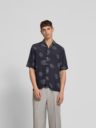 Männermodel trägt Relaxed Fit Langarmbluse aus Viskose von Officine Générale, dunkelblau mit Muster, durchgehende Knopfleiste, Reverskragen, 3/4-Arm, Rückenlänge bei Größe M 80 cm, Schulterbreite 47 cm, Ärmellänge 33 cm, Ganzkörperansicht von vorne.
