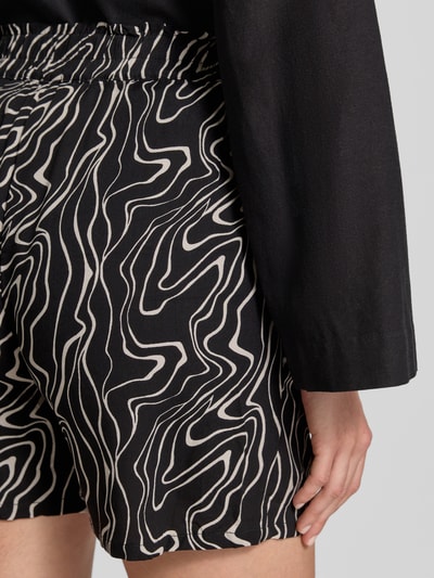 Frauenmodel trägt Loose Fit Shorts aus reiner Viskose Modell 'EASY JOY' von Vero Moda mit Allover-Muster, Detailaufnahme Rückansicht.