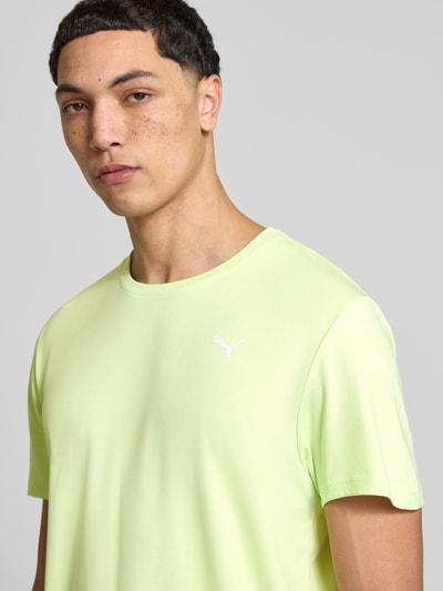 Männermodel trägt TRAINING T-Shirt mit Label-Detail Modell von PUMA PERFORMANCE, hellgrün, Kurzärmelig, Rundhalsausschnitt, Nahaufnahme Oberkörper.