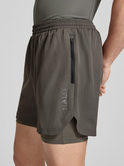 Männermodel trägt Shorts im 2-in-1-Look von HALO in Dunkelgrau, Material-Mix mit Stretch-Anteil, elastischer Bund, Nahaufnahme Oberkörper.