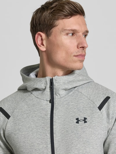 Männermodel trägt Regular Fit Jacke mit Kapuze Modell 'Unstoppable' von Under Armour, hellgrauer Baumwollmix, Nahaufnahme Oberkörper.
