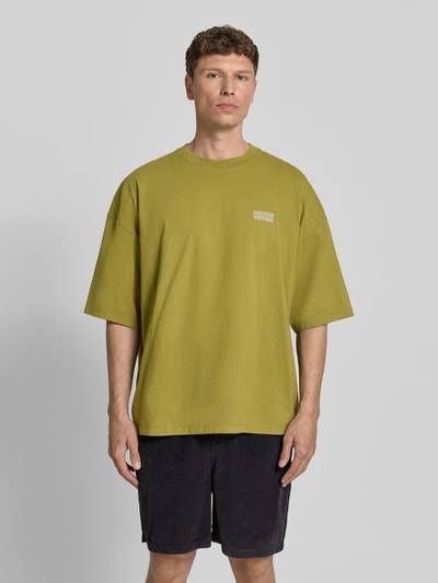 Männermodel trägt Herren T-Shirt mit Logo-Print Modell 'GIXY' von American Vintage in grün, Reine Baumwolle, Loose-Fit, Ganzkörperansicht von vorne.