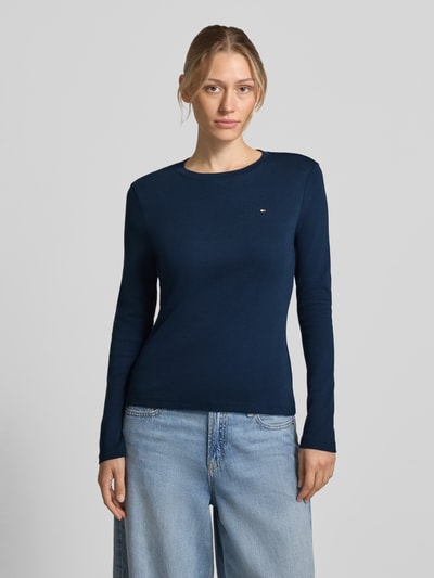 Frauenmodel trägt Slim Fit Langarmshirt aus reiner Baumwolle von Tommy Hilfiger in Dunkelblau, kombiniert mit hellblauer Jeans, Ganzkörperansicht von vorne. Damen Langarmshirt von Tommy Hilfiger.