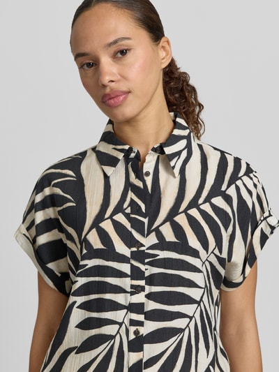 Frauenmodel trägt Bluse aus Viskose-Mix mit Hemdblusenkragen Modell 'LIFE' von Mango, grafisches Schwarz-Beige-Muster, Nahaufnahme Oberkörper, Damen Bluse, Straight Fit, Knopfleiste, Ärmel mit fixiertem Aufschlag, Rückenlänge bei Größe S 53 cm, Ärmellänge bei Größe S 15 cm, strukturierte Oberfläche.
