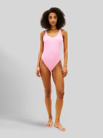 Frauenmodel trägt Badeanzug mit Logo-Stitching von TOMMY HILFIGER in Rosa, Optik: Unifarben, Materialverarbeitung: Crinkle, Ganzkörperansicht von vorne.