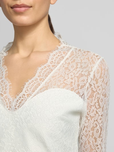 Frauenmodel trägt tailliertes Brautkleid mit V-Ausschnitt Modell 'Joanna' von GUIDO MARIA KRETSCHMER WOMAN aus Elastischer-Material-Mix, Oberteil aus Spitze, cremeweiße Farbe, Nahaufnahme Oberkörper.