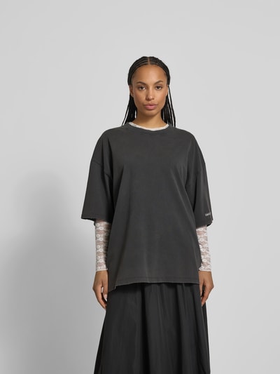 Frauenmodel trägt Oversized T-Shirt mit Label-Stitching von black palms aus reiner Baumwolle, Rundhalsausschnitt, Abschlüsse im Destroyed-Look, Rückenlänge 77 cm, Farbe Schwarz, Ganzkörperansicht von vorne.