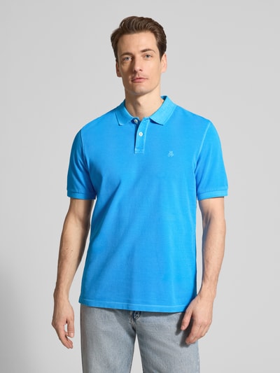 Männermodel trägt Regular Fit Poloshirt aus reiner Baumwolle von Marc O’Polo in Uni-Blau mit Polokragen und Logo-Stitching, Nahaufnahme Oberkörper.