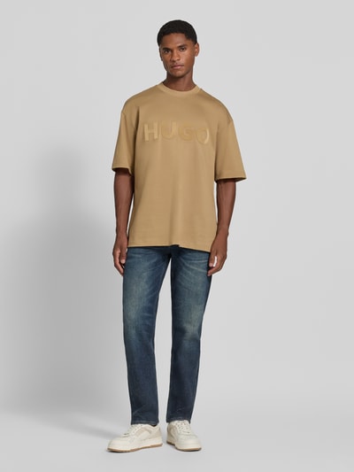 Mannelijk model draagt Regular Fit T-shirt uit zuiver katoen model 'Dinkee' van HUGO, beige met reliëfletters, Heren t-shirt, volledig frontaal.
