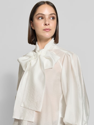 Frauenmodel trägt Regular Fit Langarmbluse aus Lyocell-Mix von Jake*s Collection in Creme mit großer Schleife, leichte Struktur, Nahaufnahme Oberkörper.