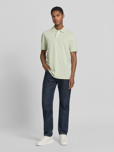 Męski model nosi Regular Fit Poloshirt aus reiner Baumwolle Modell 'PRIME' von BOSS Orange, efekt: jednolity kolor, naszywka z logo, kołnierzyk polo, dekolt w serek, krótkie zapięcie na guziki, krótki rękaw, zakończenia rękawów prążkowane, wykończenie materiału: pika, materiał: bawełna, ganzkörperansicht von vorne.
