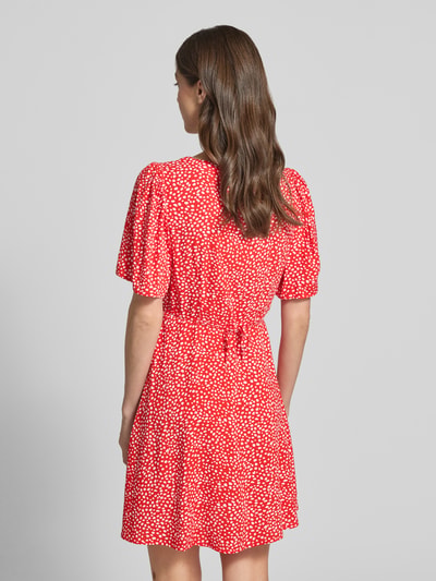 Frauenmodel trägt Leicht ausgestelltes Minikleid aus reiner Viskose Modell 'ALBA' von Vero Moda in Rot mit weißen Punkten, Rückansicht.