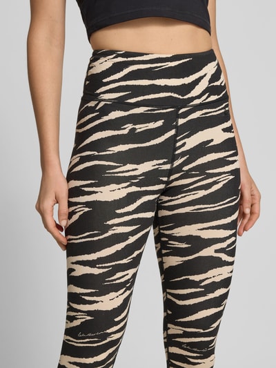 Frauenmodel trägt Slim Fit Leggins aus Viskose-Mix von Lala Berlin mit Allover-Animal-Print, Logo-Detail, Knöchellänge, Nahaufnahme Oberkörper.