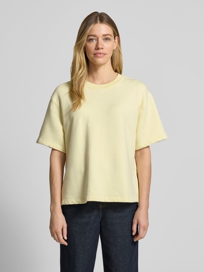 Frauenmodel trägt Sweatshirt mit 1/2-Arm und Rundhalsausschnitt von Rich & Royal im Loose-Fit aus Bio-Baumwoll-Mix mit Stretch-Anteil, überschnittene Schultern, seitliche Schlitze, einfarbig hellgelb, weiche Textur, Ganzkörperansicht von vorne.