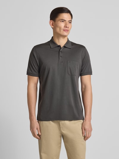 Męski model nosi Regular Fit Poloshirt mit Brusttasche od RAGMAN, ciemnoszary kolor, bawełna, kieszeń, logo, widok całej sylwetki z przodu.