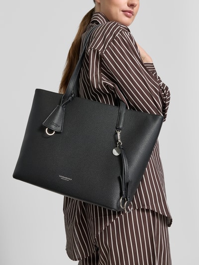 Frauenmodel trägt Shopper mit Label-Detail Modell 'LOHJA' von Seidenfelt in Schwarz, grobe Struktur, Anhänger, Ganzkörperansicht von vorne. Hauptfach mit Reißverschluss, Lange Tragegriffe, Reißverschlussfach innen, Breite 41 cm, Länge 29 cm, Tiefe 68 cm, Länge Schulterriemen 12 cm.