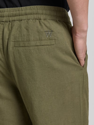 Männermodel trägt Regular Fit Hose mit Eingrifftaschen van Wood Wood, mix van linnen en katoen, elastische band, steekzakken, detailaufnahme achterzijde.