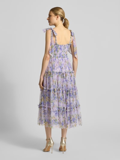 Frauenmodel trägt Cocktailkleid im Stufen-Look von LACE & BEADS aus Tüll in Flieder mit floralen Mustern, Smok-Details, Schnürungen, A-Linie, Ganzkörperansicht Rückansicht, Rückenlänge bei Größe S: 102 cm, Brustweite bei Größe S: 34 cm.