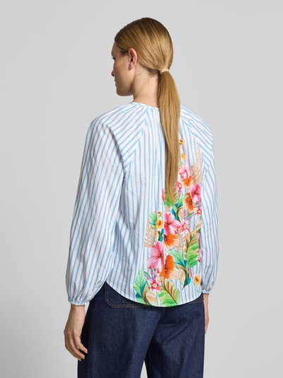 Frauenmodel trägt Regular Fit Bluse im Allover-Look mit V-Ausschnitt von Emily Van den Bergh aus reiner Baumwolle, Streifenmuster, Rückseite mit floralen Mustern, Farben Blau, Weiß, Bunt, Rückansicht, Rückenlänge 51 cm, Ärmellänge 71 cm, Ganzkörperansicht Rückansicht.