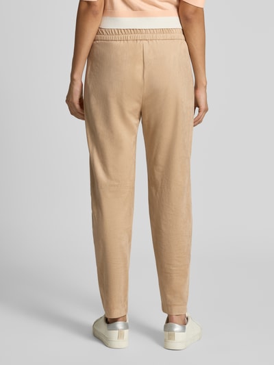 Frauenmodel trägt Stoffhose mit Stretch-Anteil von Marc Cain in Beige, elastischer Bund, ballonförmiger Schnitt, Ganzkörperansicht Rückansicht.