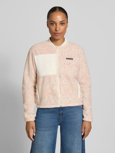 Modelka kobieca nosi Regular Fit Jacke mit Stehkragen od Columbia, beżowy polar, łatka z logo, kieszeń napoleonka i wsuwana, zamek, krótka, szerokość w rozmiarze S: 50 cm, długość tyłu: 49 cm, szerokość ramion: 44 cm, długość rękawa: 61 cm, widok całej sylwetki z przodu