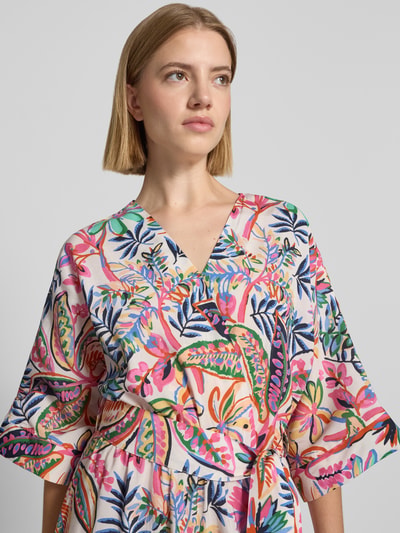 Frauenmodel trägt Midikleid aus Viskose-Mix mit floralem Allover-Print von Milano Italy in bunten Farben, Nahaufnahme Oberkörper. Taillierte Passform, abnehmbares Taillenband, Halbarm, V-Ausschnitt und Wickel-Optik sind erkennbar.