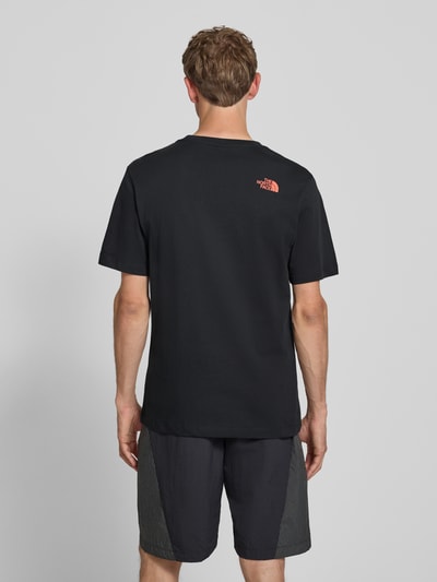 Männermodel trägt T-Shirt mit Label-Print und Rundhalsausschnitt von The North Face aus Reine Baumwolle im Regular-Fit, Rückenlänge 74 cm, Ganzkörperansicht Rückansicht.