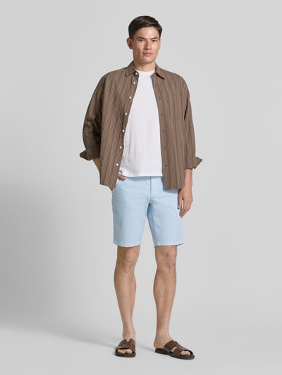 Männermodel trägt Regular Fit Bermuda aus Baumwoll-Mix von Brax in Hellblau, kombiniert mit Braun und Weiß, Ganzkörperansicht von vorne. Herren Bermuda von Brax.