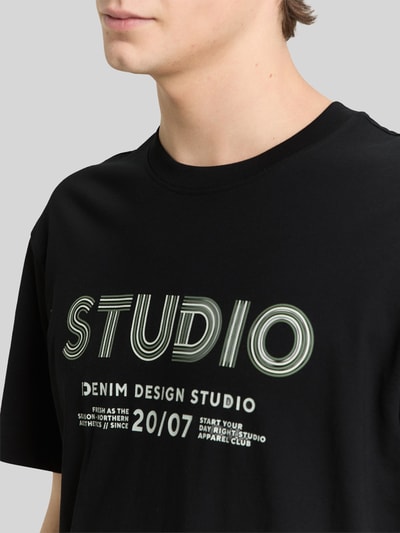 Männermodel trägt Relaxed Fit T-Shirt aus reiner Baumwolle von Tom Tailor Denim mit Label-Print, Optik: Unifarben, Nahaufnahme Oberkörper.