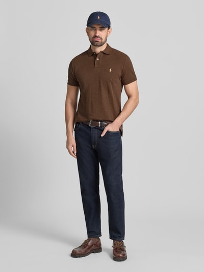 Mężczyzna nosi Slim Fit Poloshirt aus reiner Baumwolle od Polo Ralph Lauren w kolorze brązowym, krój slim fit, logo na piersi, polówkowy kołnierz, bawełniana faktura piqué, gładka powierzchnia, krótkie rękawy, widok całej sylwetki z przodu.