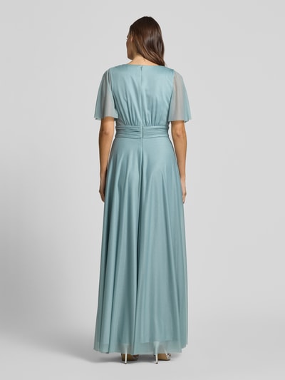 Frauenmodel trägt Schimmerndes Maxikleid mit V-Ausschnitt und Taillenband von Christian Berg Cocktail aus Mesh in A-Linie, schimmernde Textur, Rückenlänge bei Größe 36: 149 cm, Brustweite: 35 cm, Ärmellänge: 29 cm, Ganzkörperansicht Rückansicht.