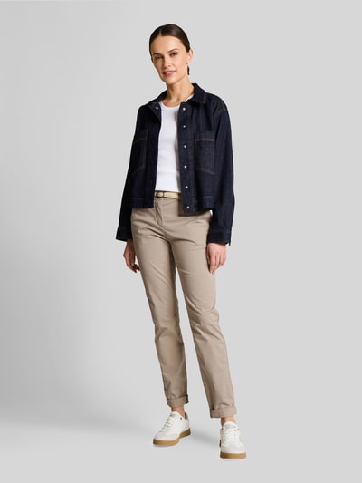 Frauenmodel trägt Slim Fit Chino aus Baumwoll-Mix von Tom Tailor in Optik: Unifarben mit Gürtel, Kontrastnähte, Beinabschluss Umschlag, seitliche Eingrifftaschen, Gesäßtaschen, Ganzkörperansicht von vorne.