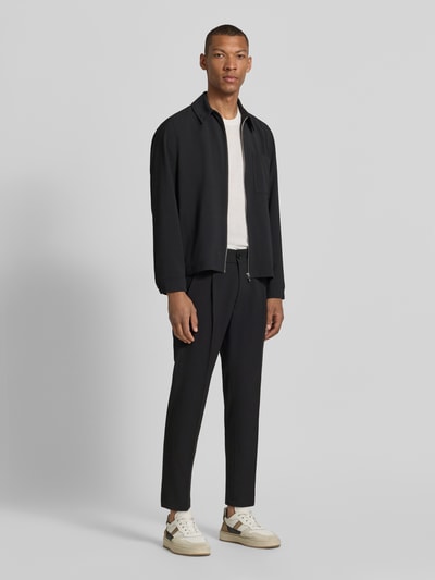 Männermodel trägt Hose mit Gesäßtaschen Modell 'CHASY' von Drykorn, Slim-Fit, Material-Mix mit Baumwoll-Anteil, Ganzkörperansicht von vorne.