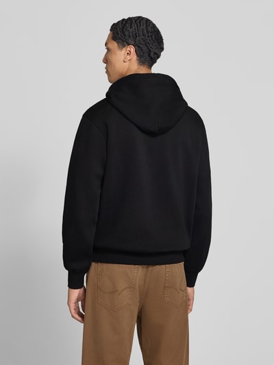 Männermodel trägt Hoodie aus Baumwoll-Mix Modell 'FREDERIKS' von JACK & JONES in Schwarz und Braun, Ganzkörperansicht Rückansicht.