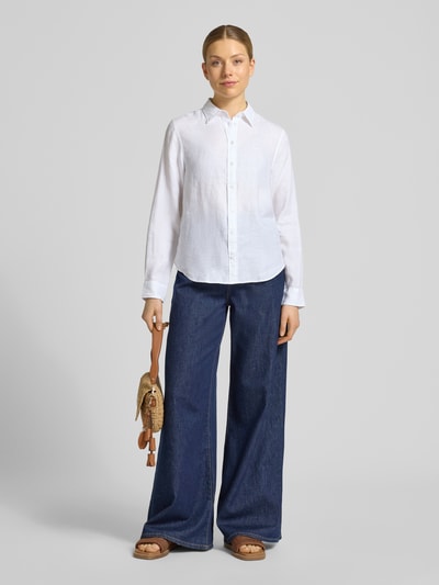 Frauenmodel trägt Regular Fit Leinenbluse mit Label-Stitching von Gant aus reinem Leinen mit Hemdblusenkragen, Knopfleiste, weiße Farbe, glatte Textur, Rückenlänge bei Größe 36: 66 cm, Ärmellänge 60 cm, Ganzkörperansicht von vorne.