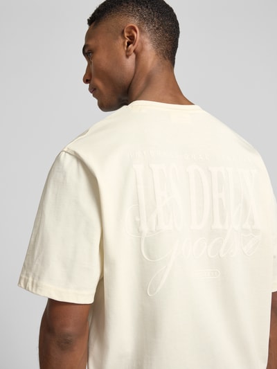 Männermodel trägt T-Shirt mit Label-Print Modell 'Ben Goods' von Les Deux in Creme, reine Bio-Baumwolle, gerader Schnitt, Ganzkörperansicht Rückansicht.