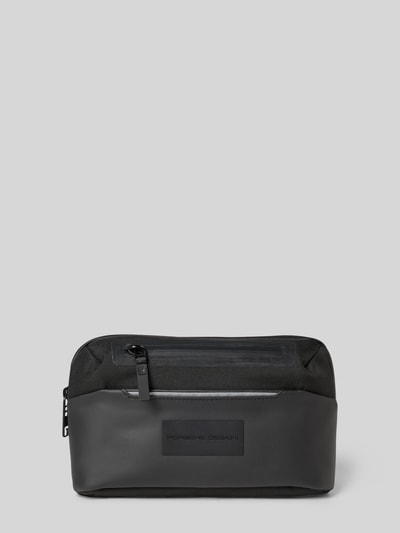 Produktfoto, Tasche mit Label-Detail von Porsche Design mit Reißverschluss-Hauptfach, versteckte Rückseite, reflektierende Streifen, Längenverstellbar, schwarze Oberfläche, glatte und textile Textur.