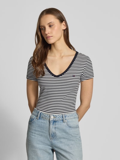 Vrouwenmodel draagt Slim Fit T-Shirt uit katoenmix van Tommy Jeans, two tone strepen, logo-stitching, ribstructuur, v-hals, korte mouw, vooraanzicht bovenlichaam.