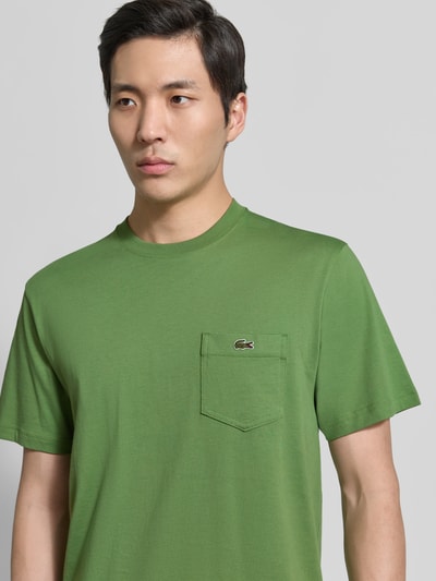 Męski model nosi Regular Fit T-Shirt aus reiner Baumwolle von Lacoste, efekt: jednolity kolor, wyhaftowane logo, nadruk z logo, okrągły dekolt, bawełna, półzbliżenie przód.